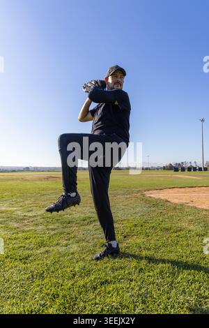 Mature man in sportswear standing on pitcher's mound with cap, glove and cleats preparing pitch Stock Photo