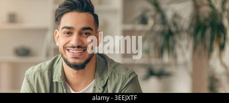 Young Man Smiles While Sitting Indoors With Plants in Background During Daytime Stock Photo