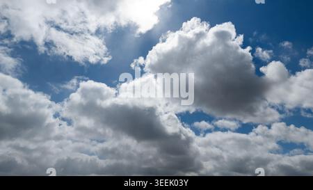 Bright sky with clouds while sun shining through white fluffy clouds in professi Stock Photo