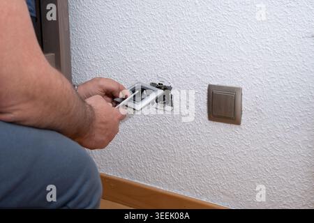 Man installing an electrical outlet with a screwdriver for repair or renovation Stock Photo