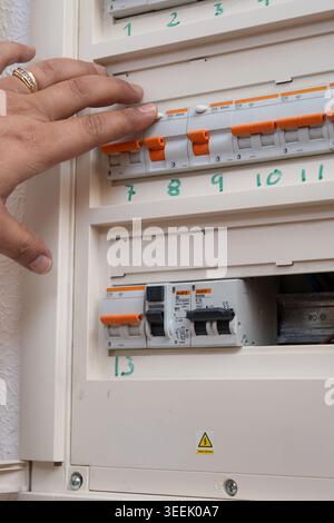 Hand pressing reset button on circuit breaker in residential electrical panel Stock Photo