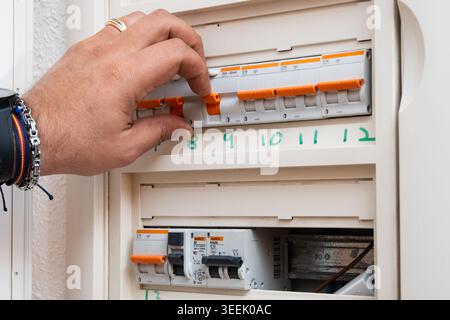 Hand turning a circuit breaker in an electrical power distribution box Stock Photo