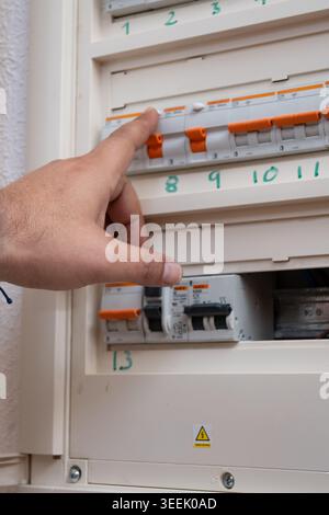 Hand activating power switch in electrical panel, checking electricity Stock Photo