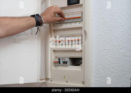 Hand activating a circuit breaker in a home fuse box, restoring electricity Stock Photo