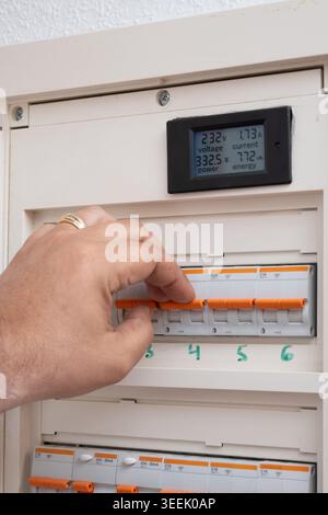 Person adjusting power supply using electrical circuit breakers and monitoring voltage Stock Photo