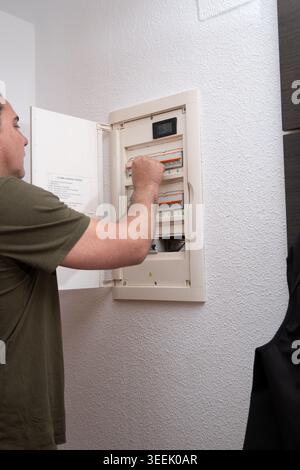 Man inspecting circuit breaker switch in home electrical panel Stock Photo