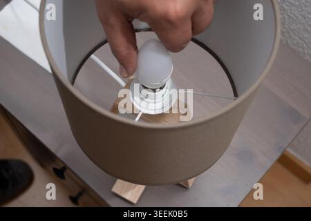 Person replacing an old light bulb with a new LED bulb in a modern lamp Stock Photo