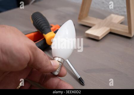 Hand holding modern LED light bulb ready for installation in a home fixture Stock Photo