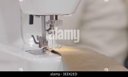 Sewing machine in focus while working on fabric in professional workshop in prof Stock Photo