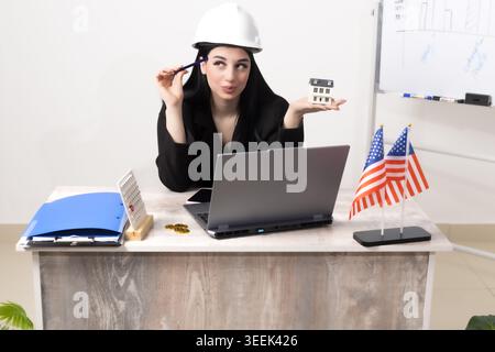 Female engineer with tablet while working in office near flag and laptop in prof Stock Photo