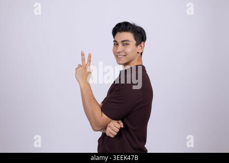 Man showing peace sign - standing and making v-sign with fingers in professional Stock Photo