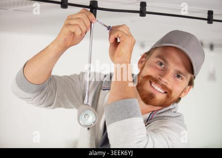 handsome young builder is twisting the light bulb in Stock Photo