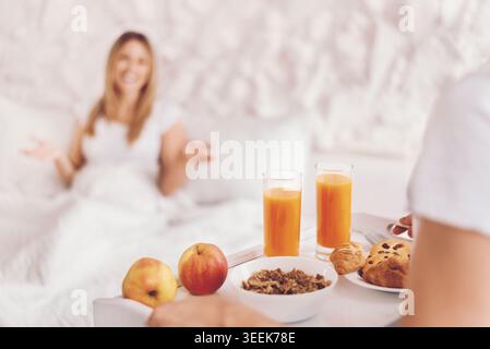 Woman Enjoys Breakfast in Bed With Juice, Fruit, and Pastries on a Tray Stock Photo