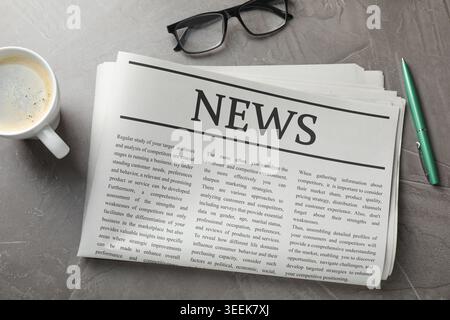 Newspaper, coffee, pen and glasses on grey table, flat lay Stock Photo