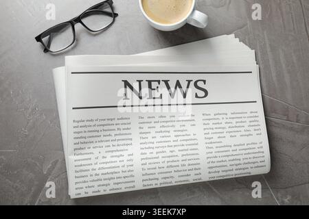 Newspaper, coffee and glasses on grey table, flat lay Stock Photo