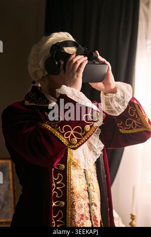 Vertical shot of man wearing historical costume and using virtual reality headset, blending past and future concepts. Ideal for innovation, digital adoption, tech campaigns Stock Photo