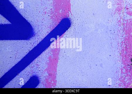 Abstract grunge painted wall texture with bold neon pink purple painted strokes and chaotic urban street art spray patterns. Stock Photo