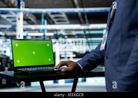 Green screen laptop used by data center employee managing infrastructure systems for uptime and efficiency. Server room admin upgrading enterprise networks hardware using mockup notebook, close up Stock Photo