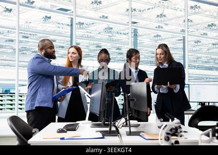 Brainstorming, microchip layout and multiethnic team in semiconductor manufacturing research facility. Optimizing PCB network topology, STEM diversity concept and multiracial coworkers using devices Stock Photo