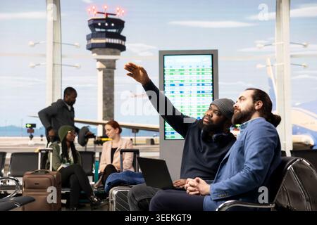 Multiethnic corporate team checking data on laptop during work trip in airport, prepared for international flight. Team of manager and assistant traveling together for global business event. Stock Photo