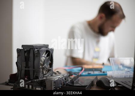 Technician working on computer parts with cooling fan in focus at home workshop in the afternoon Stock Photo