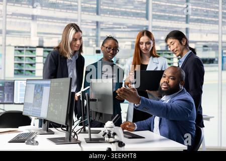 Optimizing PCB production, collaboration and multiethnic engineering team in factory research office. Developing semiconductors powering electronics, teamwork and colleagues using computer software Stock Photo