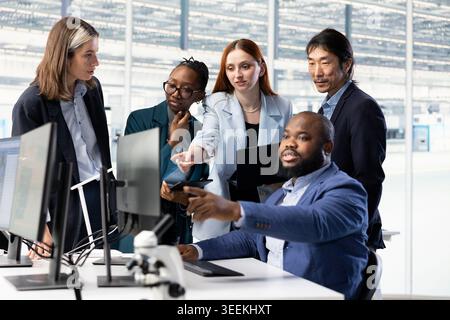 Monitoring microchip production, research and multiethnic team of technicians in industrial plant facility. Optimizing semiconductors functionality, devices and teamworking colleagues in PCB factory Stock Photo