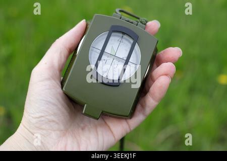 Magnetic liquid-filled compass in a palm, close-up. Useful device for hiking, trekking and map reading during adventure. Navigation concept in nature. Stock Photo