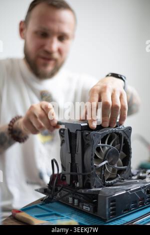 Person works on computer hardware while focusing on cooling unit installation in a well-lit indoor space Stock Photo