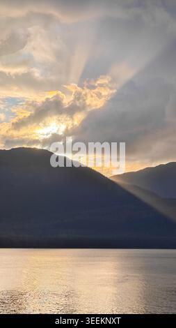 Alaska, USA - August 13 2024: Sunlight streaming through clouds over Spuhn Cove near Hoonah, Alaska, creating a dramatic scene, with mountains in the Stock Photo