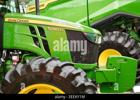 Technical close-up of a John Deere 5080E tractor, highlighting the front grille, headlight, front ballast, and high-traction agricultural tires. Stock Photo