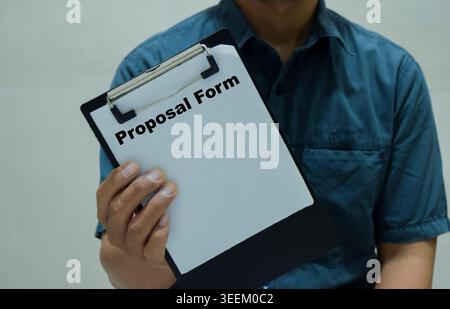 Businessman holds in hands a clipboard with the name of the proposal form. Stock Photo