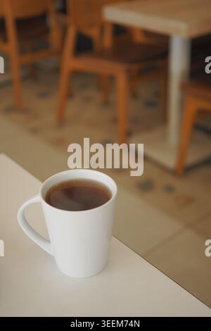 Cup of coffee sits on a table in a cafe during the day Stock Photo