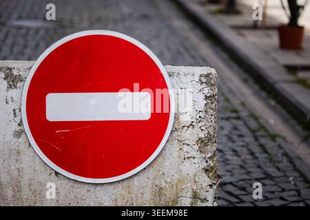 Close-up of a circular red stop sign with a white horizontal bar on a textured concrete base Stock Photo