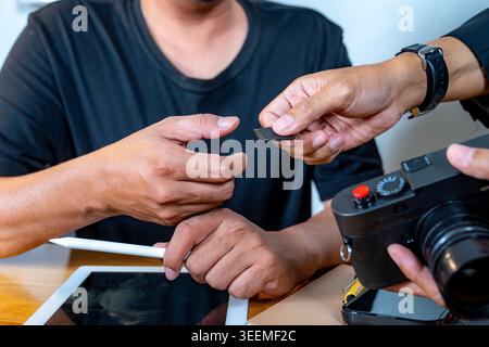 Close-up view of a photographer's hand holding a memory card, ready to be inserted into a digital camera for data storage. Stock Photo