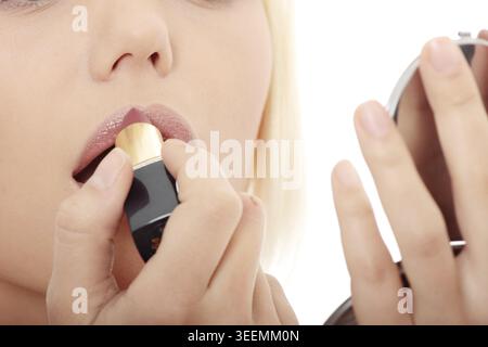 A beautiful young woman applying her make-up in the mirror Stock Photo
