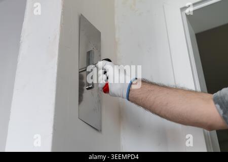 A technician applies a smooth finish to drywall using a metal trowel in a contemporary construction setting. Stock Photo