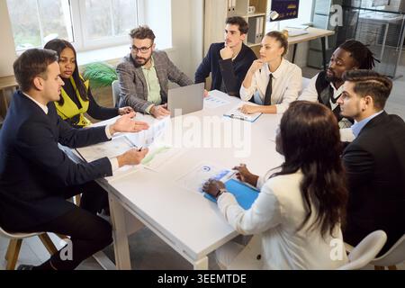 Diverse business team in office meeting discussing strategy with charts and laptop Stock Photo