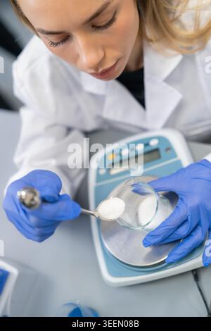 Measuring white powder using a precision laboratory scale at an analytical chemistry workstation. Stock Photo