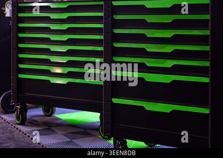 Two tool carts with green features sit on a checkered floor in a garage during daytime. Stock Photo