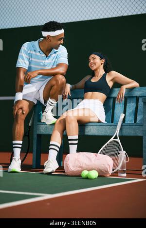 Tennis, relax and couple on court for sports competition, talking or practice with game. Outdoor, fitness and woman with partner on bench with happy Stock Photo