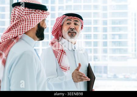 Two middle eastern business professionals conversing, sharing ideas and collaborating on a real estate project, showcasing teamwork and corporate part Stock Photo
