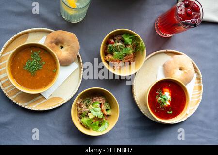 Top view of a traditional lunch with soup, salad, bread, and drinks served on a table, featuring fresh ingredients and rustic presentation in ceramic Stock Photo