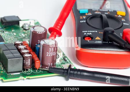 Close-up of a circuit board with electronic components and a multimeter with test probes. Concept of electronics diagnostics, electrical testing, repa Stock Photo