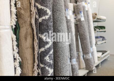 Soft rolled carpets and modern rugs displayed in flooring section of home improvement store Stock Photo