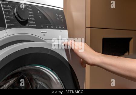 Hand opening washing machine door. operating front loading appliance in laundry room. Domestic cleaning concept for home, household, lifestyle. Stock Photo