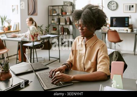 Black Adult Woman Typing on Laptop during Office Workday Stock Photo