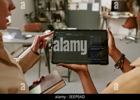 Adult Women Reviewing Software Code on Tablet in Office Stock Photo
