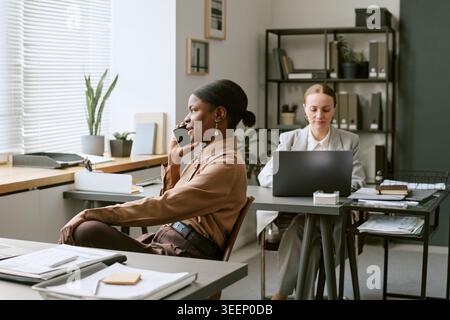 Black Woman Talking on Smartphone during Office Workday Stock Photo