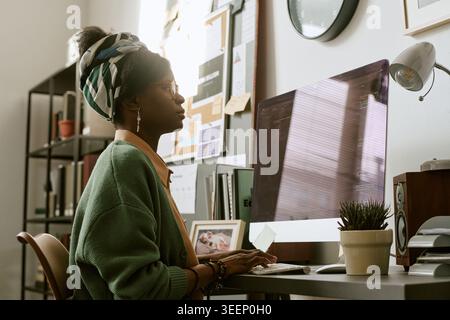 Black Adult Woman Working at Desktop Computer in Home Office Stock Photo